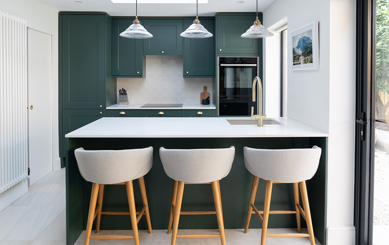 Green kitchen interior design with a breakfast bar and stools