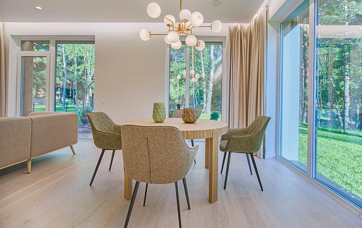 A dining room table with lighting and upholstered chairs