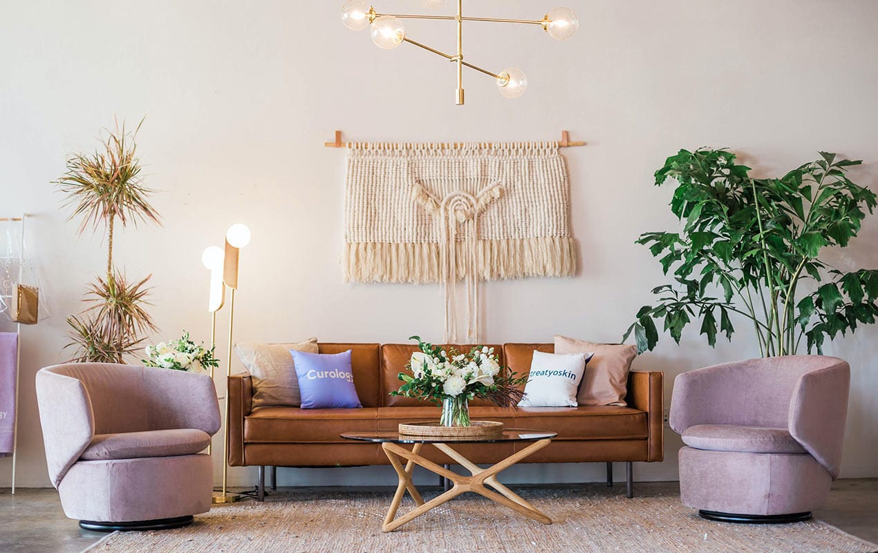 Boho decor with an orange sofa, two pink chairs, and indoor plants