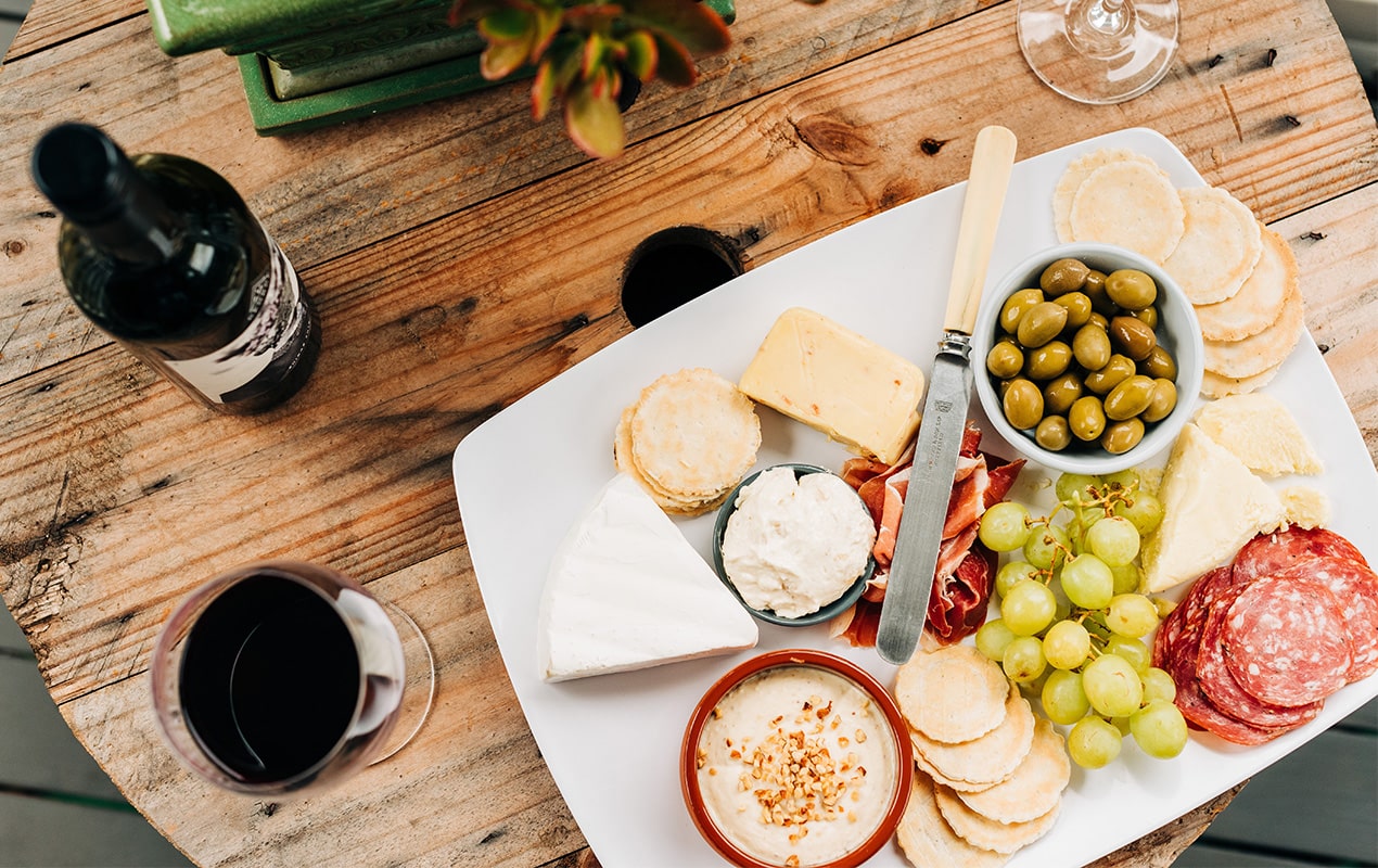 A Cheeseboard on a table with wine