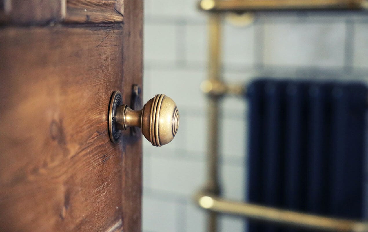 A Brass door handle, and towel rail in the background