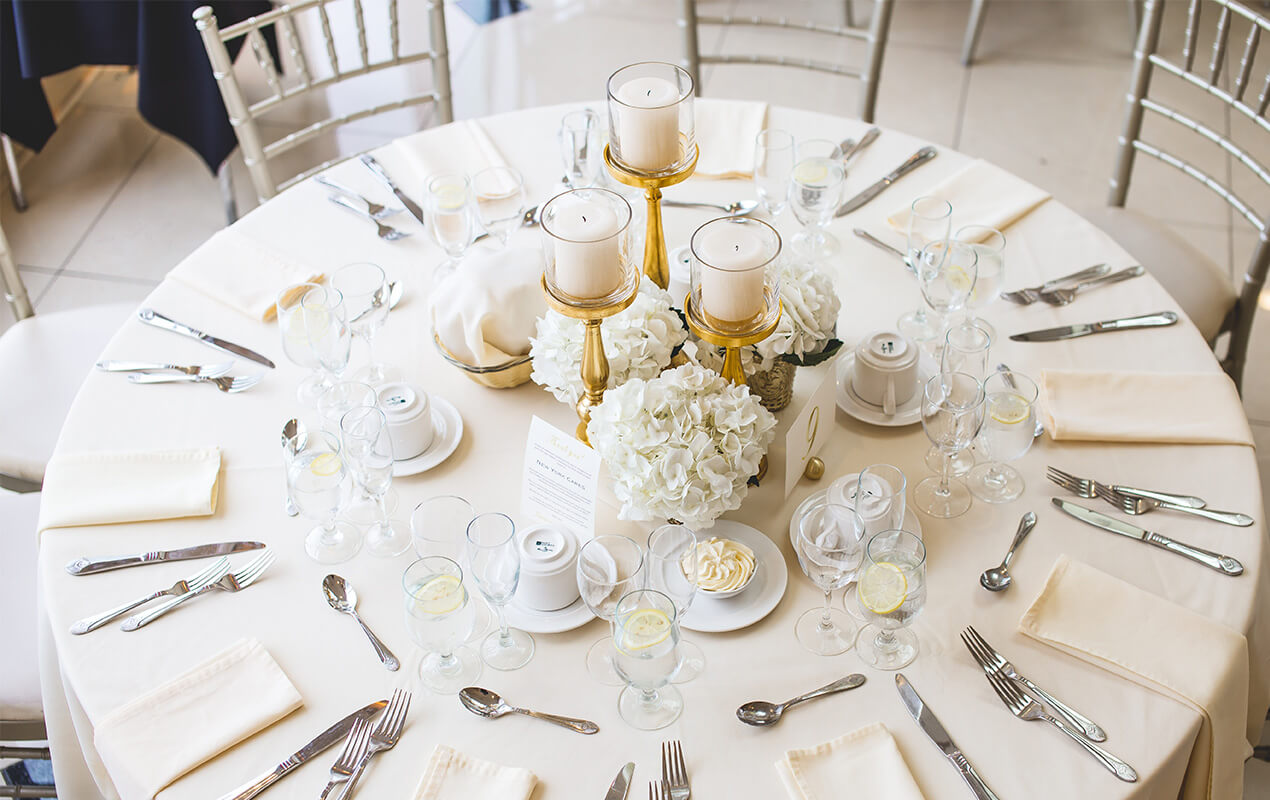 Table setting with a white table cloth, crockery, and a centrepiece