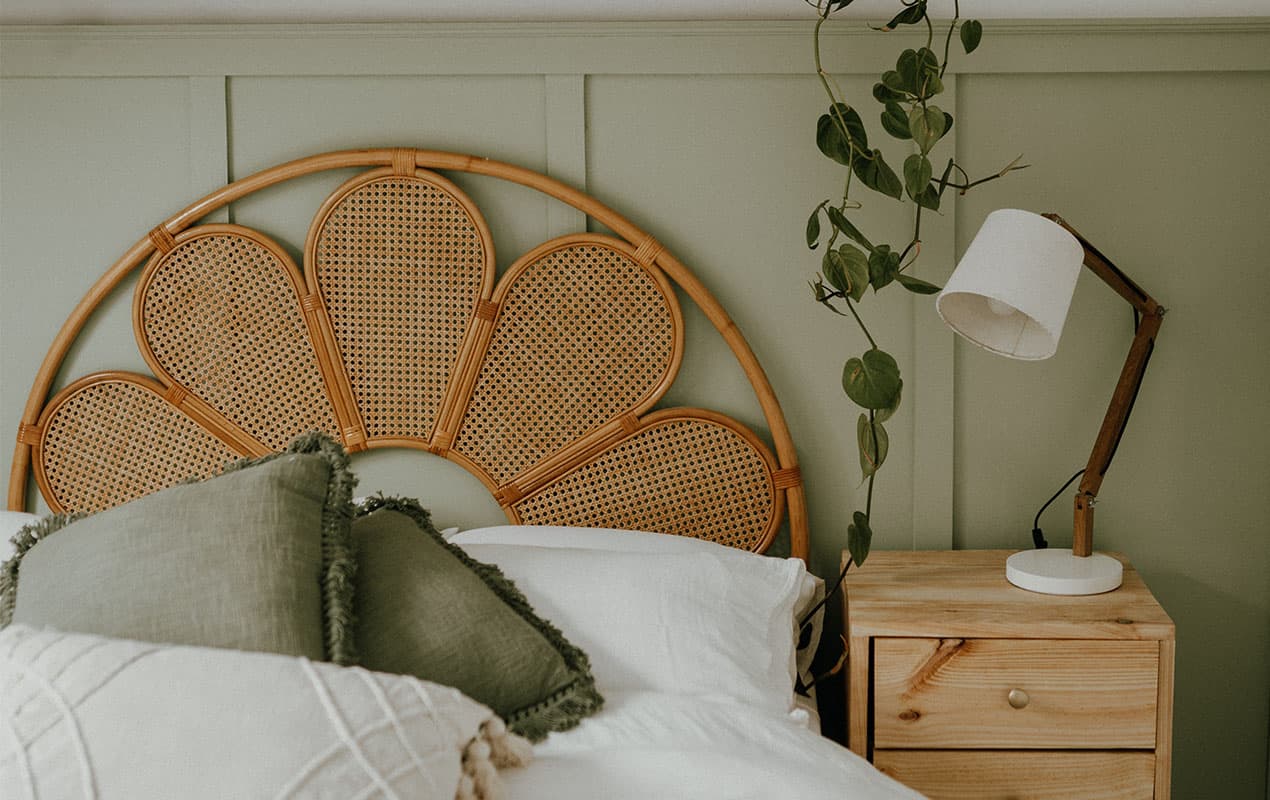 Wooden headboard with petals, in front of sage green panelled wall