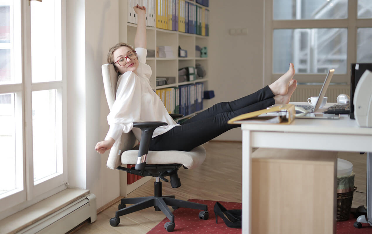 Work interior with Woman sitting on a chair with feet on desk.