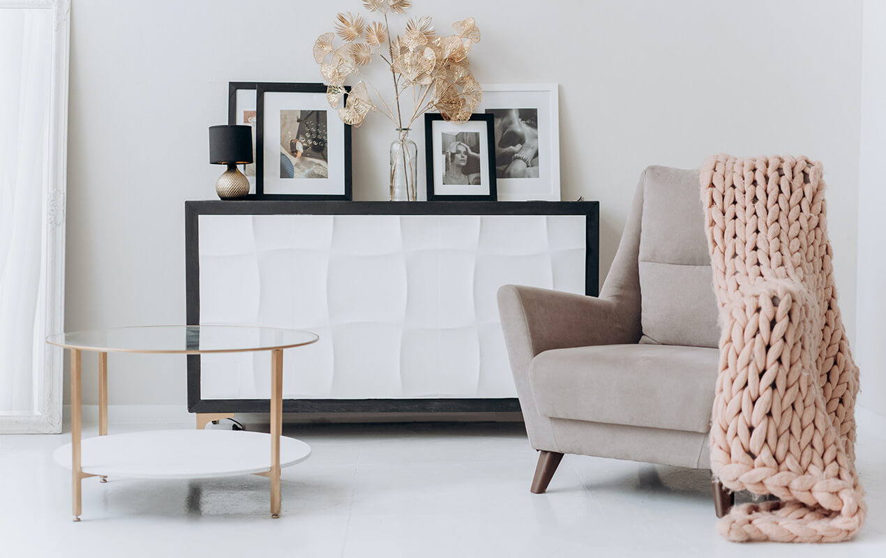 Arm chair infront of black and white cabinet with a pale pink throw