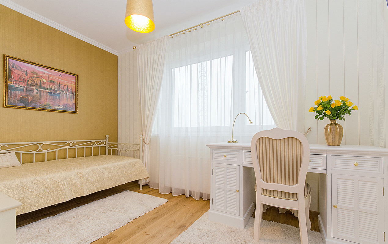 Bedroom with white long curtains, white dresser table with chair