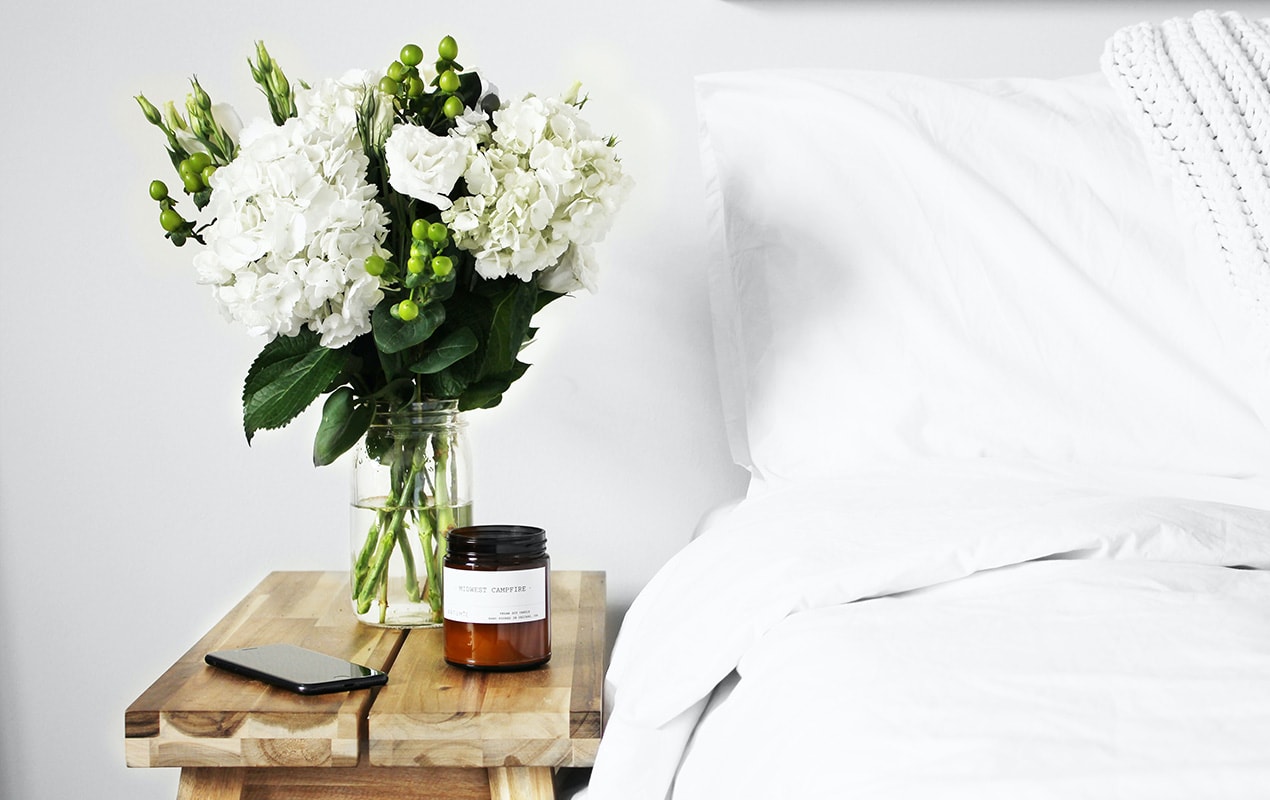Bed side table with flowers and a candle