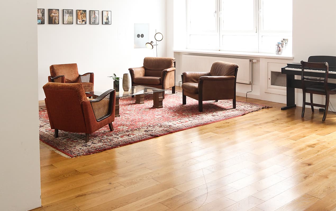 Wooden floor, floor rug and armchairs