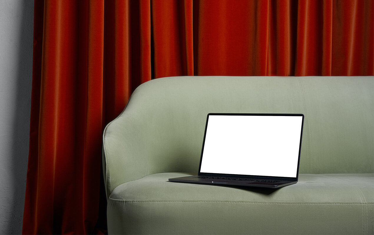 Red curtains with a green sofa and a laptop