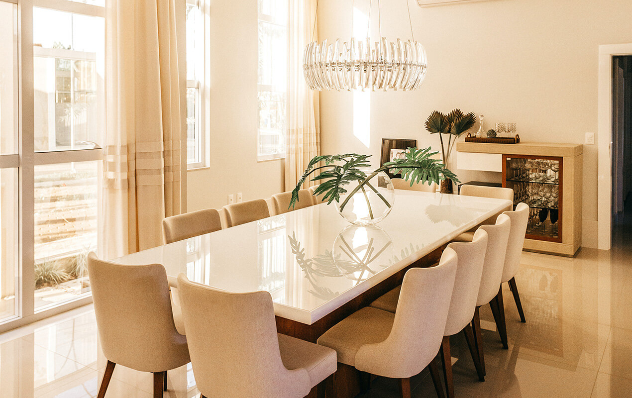 White dining room table with white chairs and a hanging chandelier