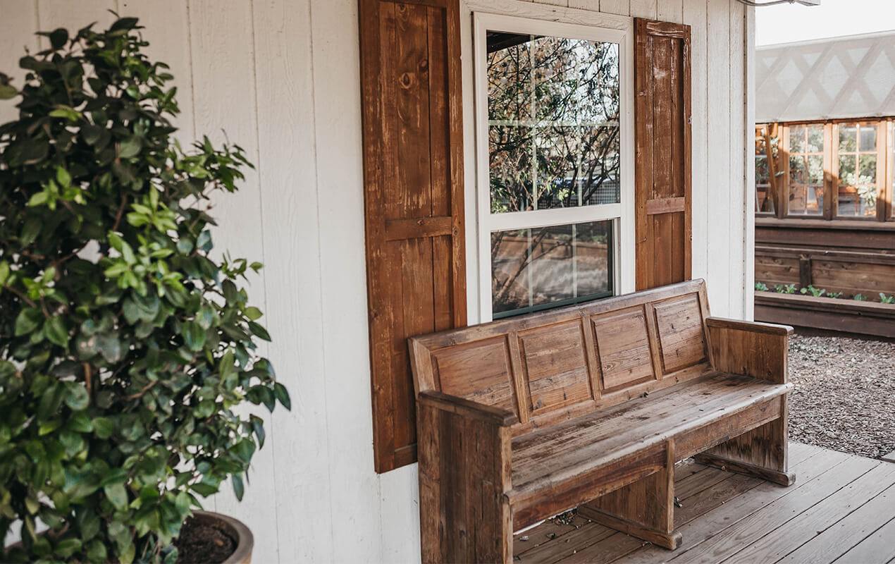 Wooden bench on porch with a tree