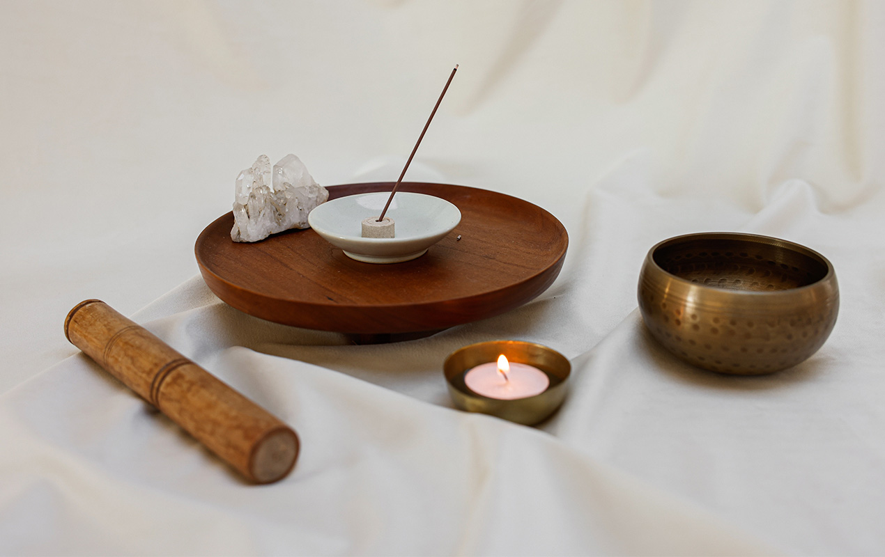 Lighted Candle, a Singing Bowl and Incense Stick on White Linen