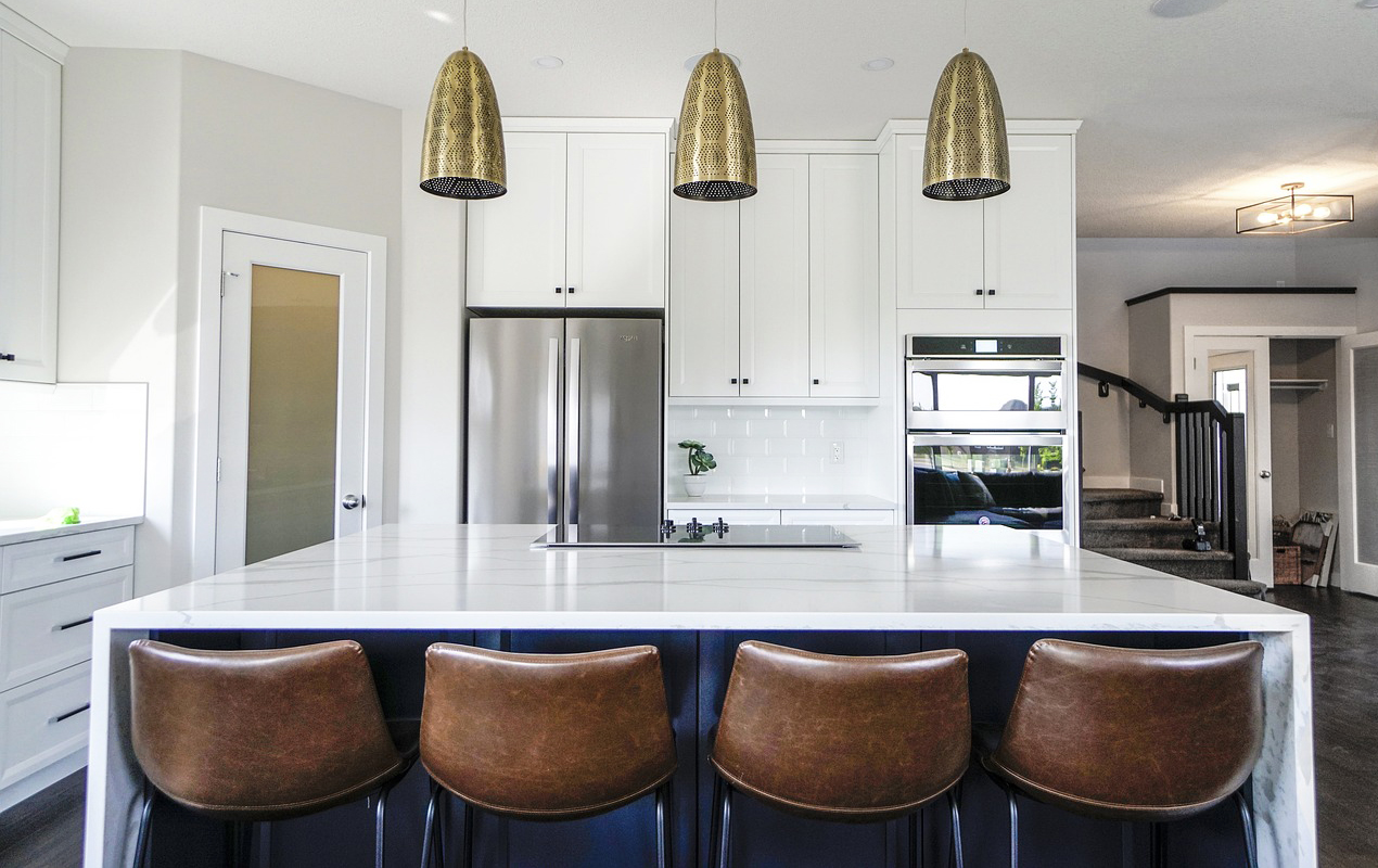 Kitchen design with brown leather chairs and gold pendant lights by DeCasa Collections