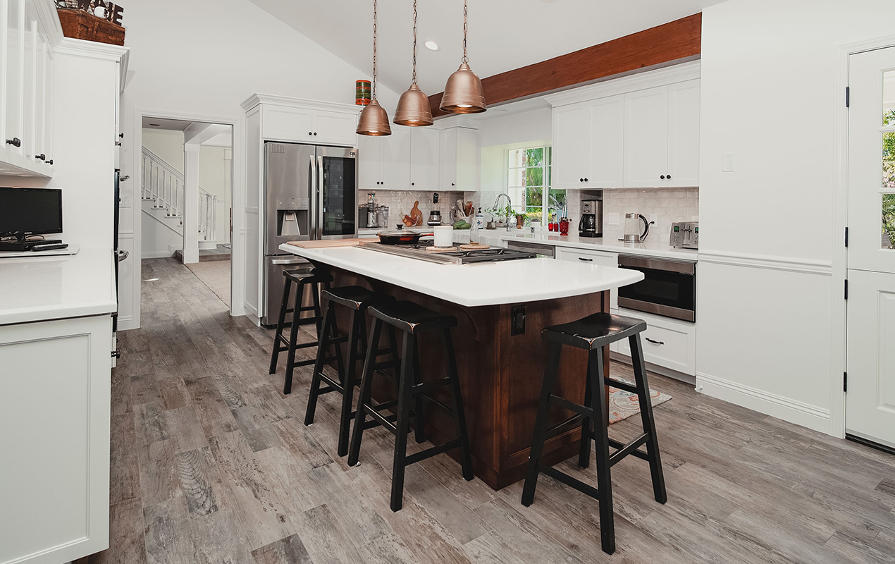 KItchen island with black stools and white countertop by DeCas Collections