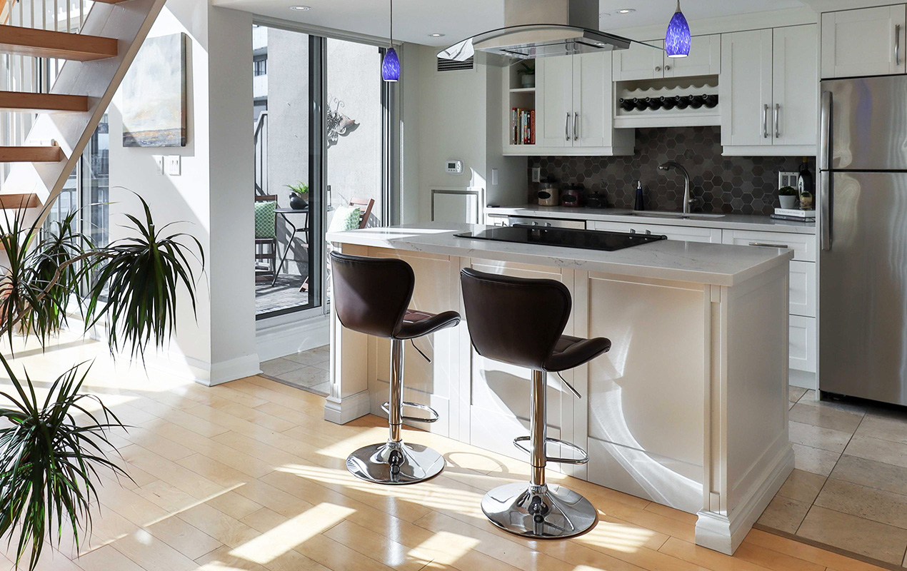 Kitchen interior with glass doors and island with gas stove by DeCasa Collections