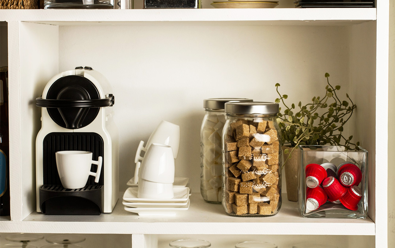 Coffee maker with accessories on white open shelves