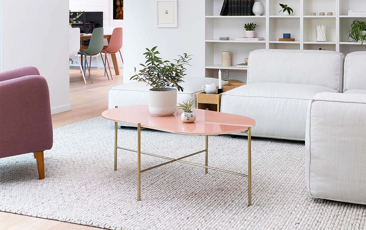 Contemporary Fashion: Pink Oval Coffee Table, Gray L-Shaped Sofa, and Maroon Accents in a Cozy Living Room