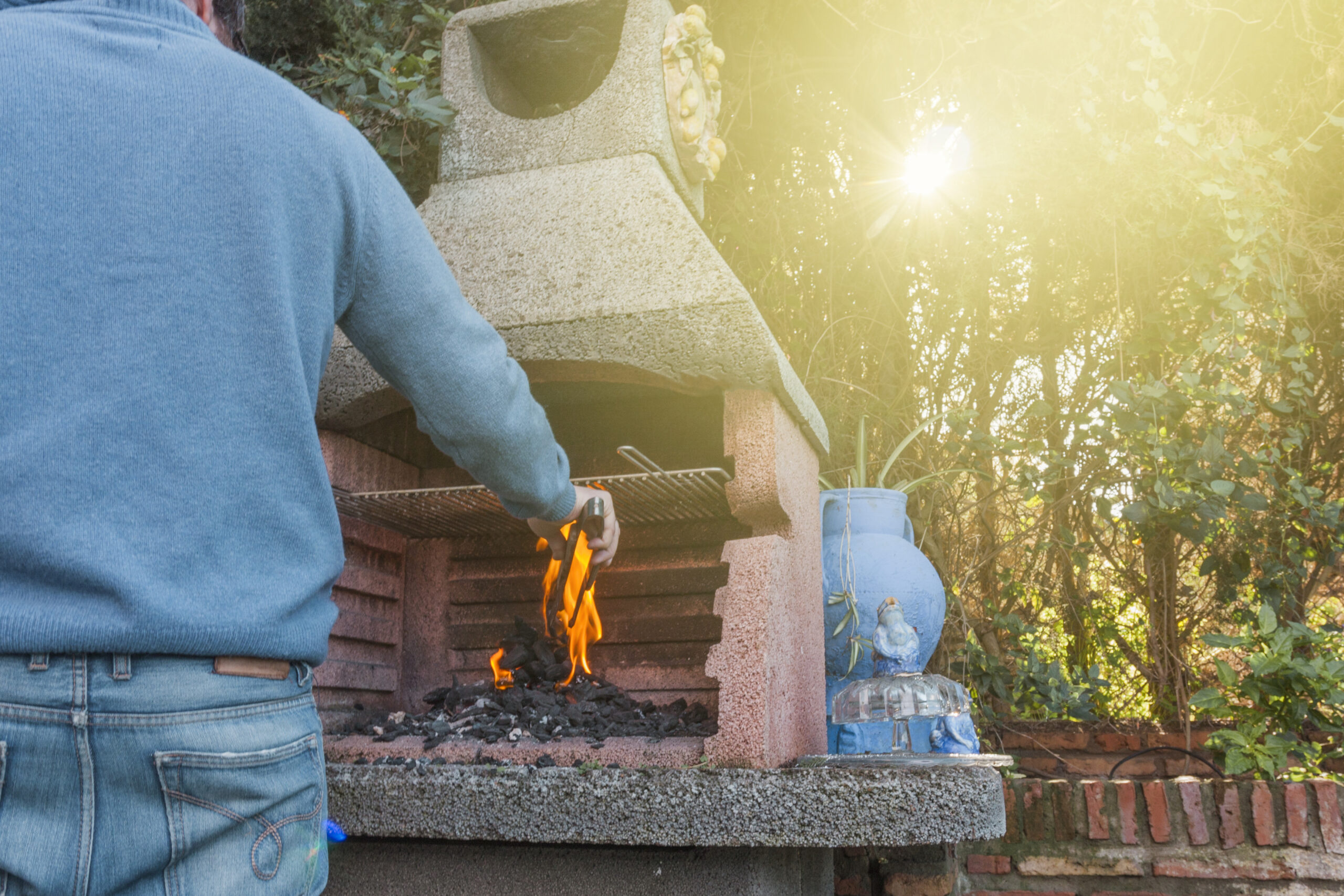 Man standing over brick smoker