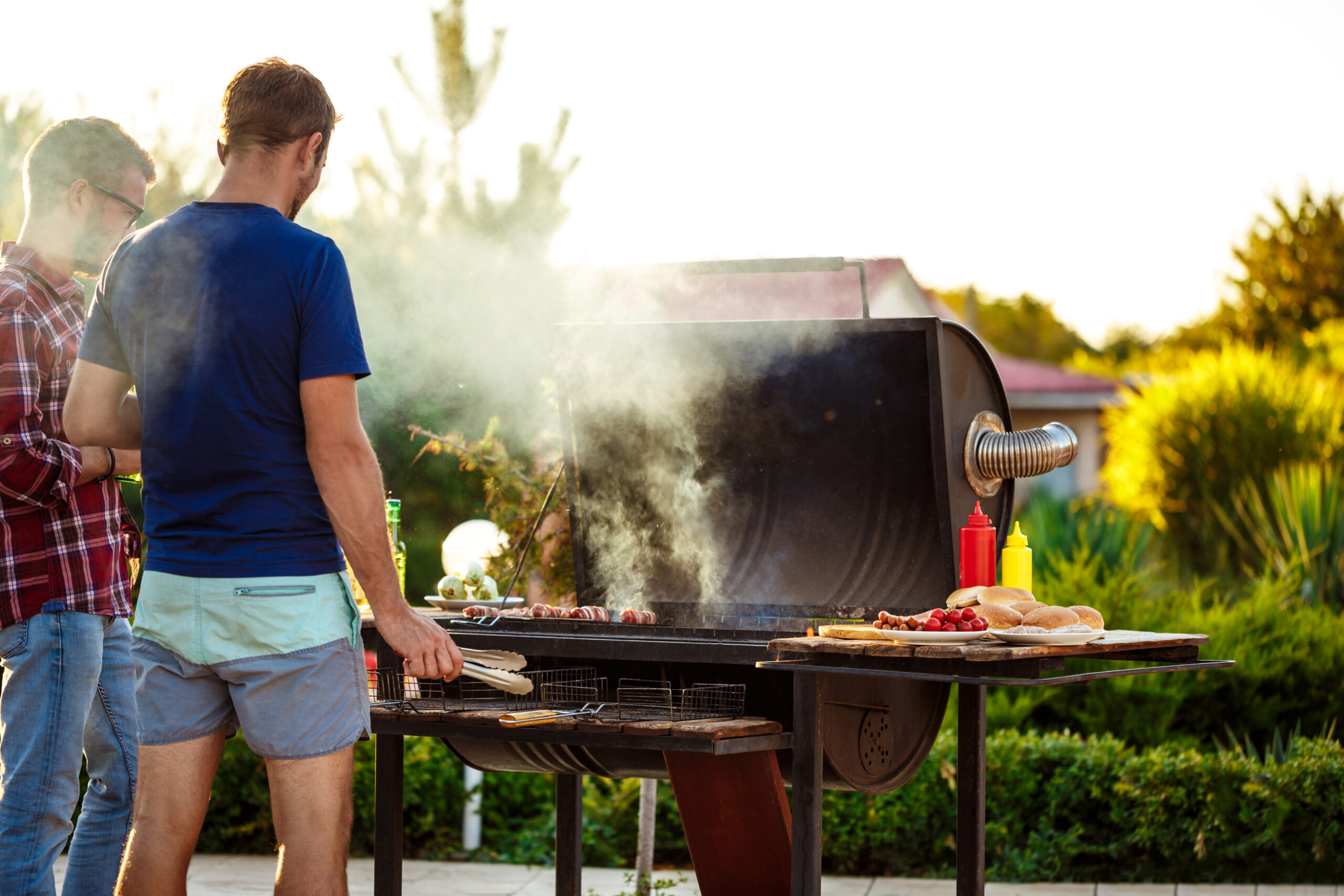 Young handsome men roasting barbecue on grill in cottage countryside. Copy space.